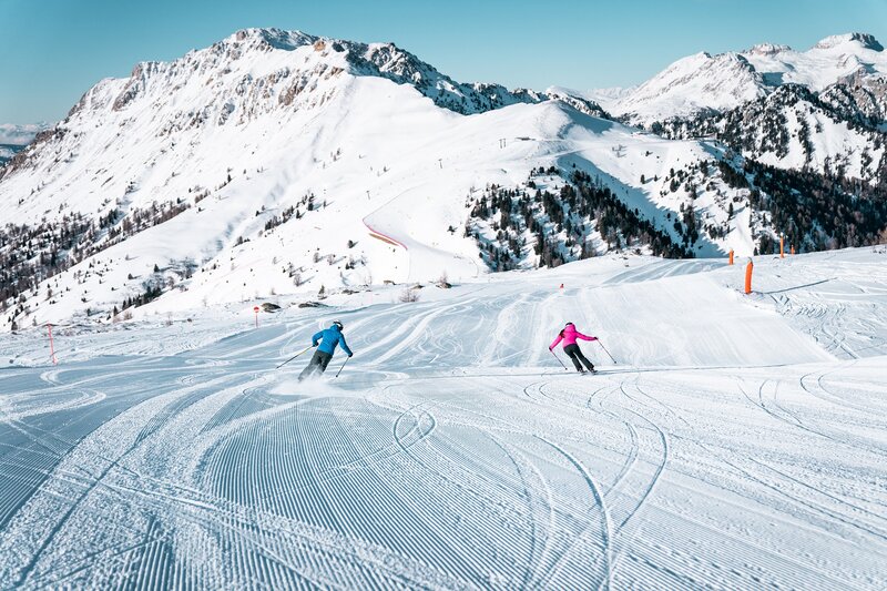 Ski area Alpe Lusia | © Camilla Pizzini - Archivio Alpe Lusia Sciatori sulle piste ai piedi delle Dolomiti nella ski area Alpe Lusia | © Camilla Pizzini - Archivio Alpe Lusia